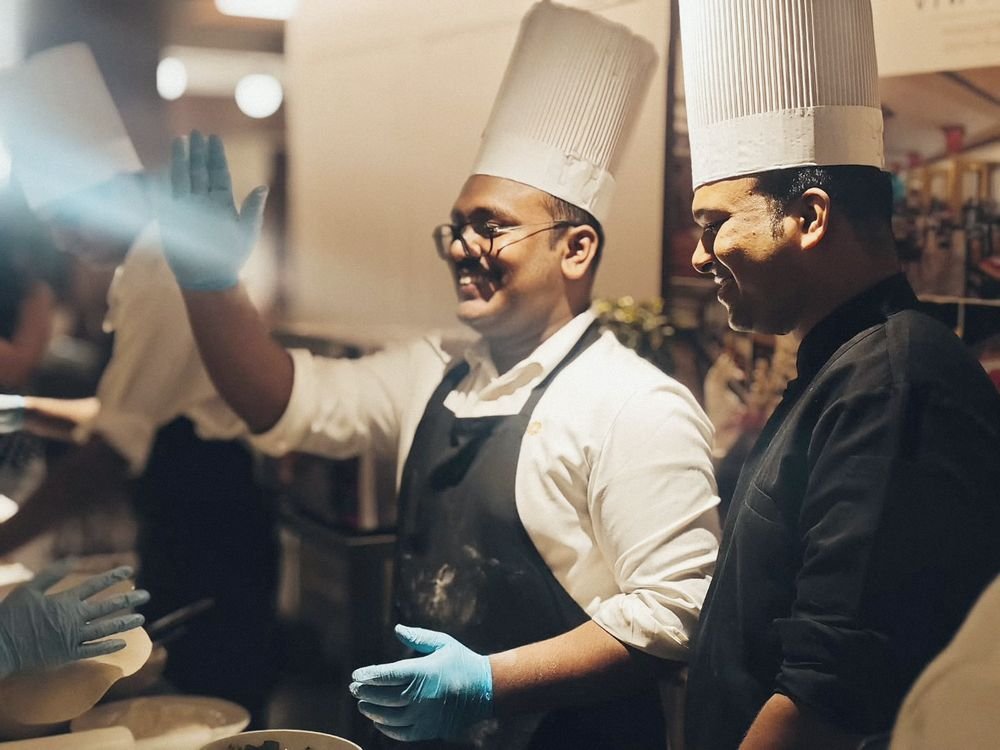 Two chefs laughing behind the counter at pizza night