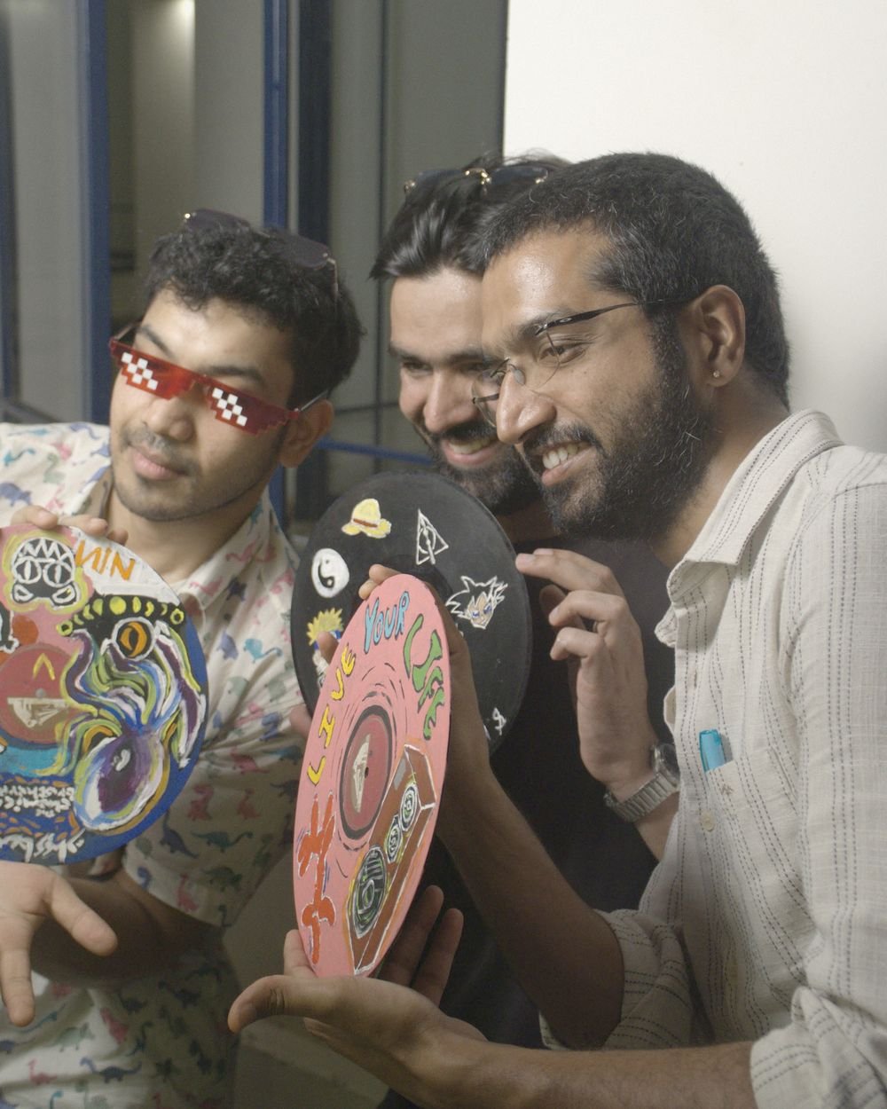 Three friends grinning over the records they painted